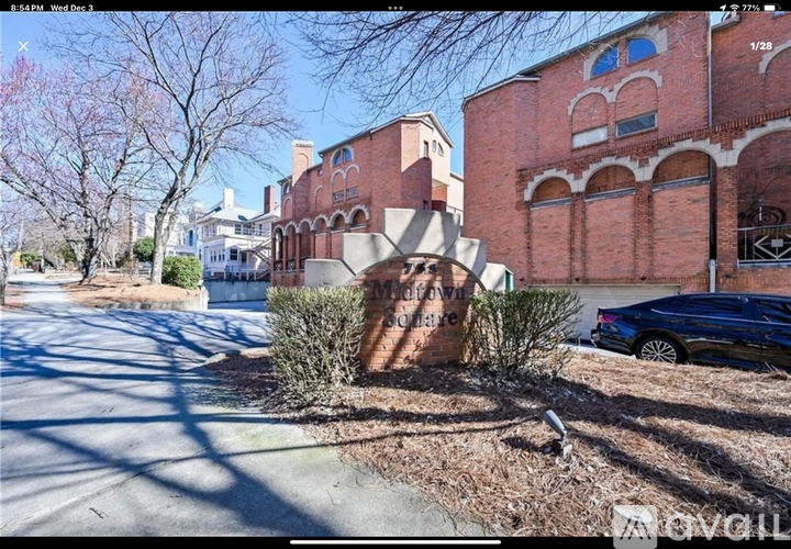 A street view of a residential area with a brick building and a car parked on the side.