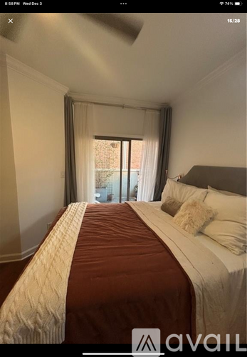 A bedroom with a large bed and a window with curtains.