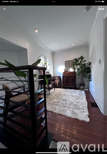 A living room with a white rug and a wooden floor.