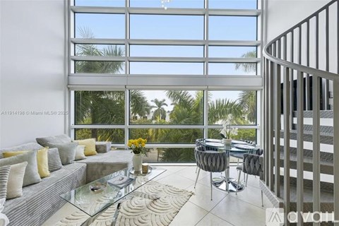 A modern living room with a spiral staircase and a glass table.