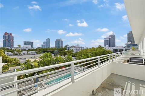 A balcony overlooks a cityscape with tall buildings and a clear blue sky.