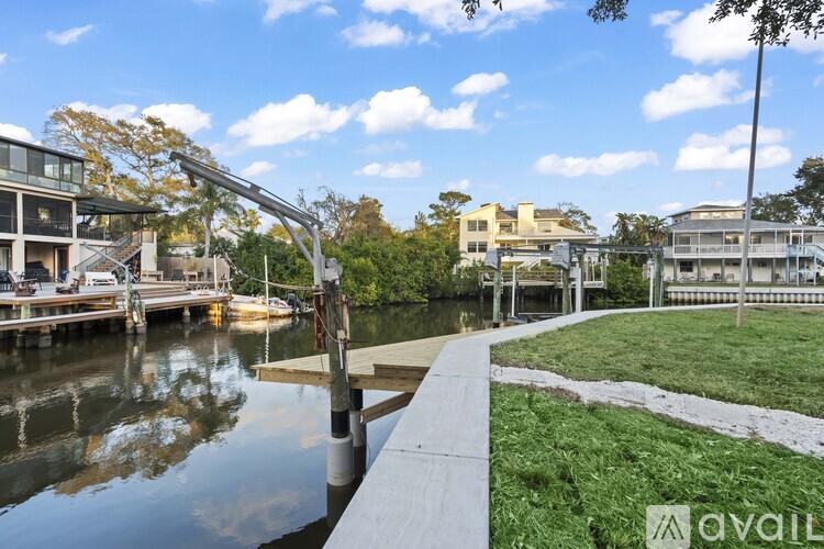 A modern house is situated on the waterfront with a dock and a grassy area in front.