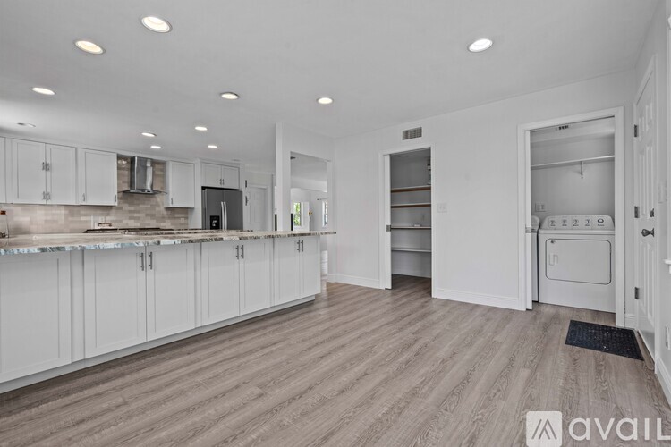 A spacious kitchen with white cabinets and a wooden floor.