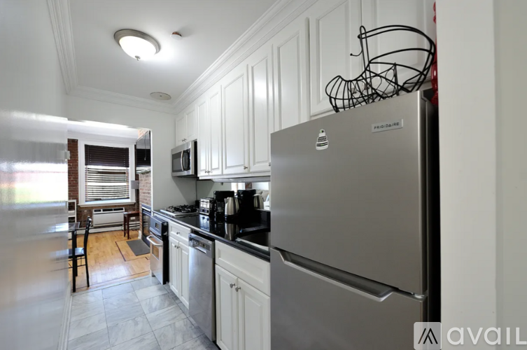 A kitchen with a stainless steel refrigerator and white cabinets.
