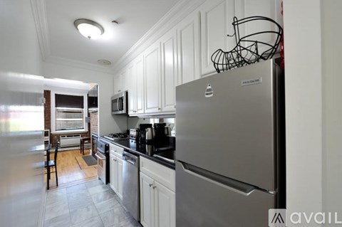 A kitchen with a stainless steel refrigerator and white cabinets.