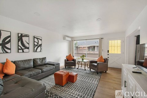 A living room with a grey couch, orange pillows, and a patterned rug.