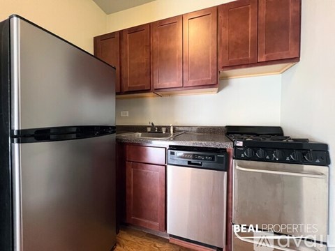 A kitchen with a black fridge, stainless steel dishwasher and oven.