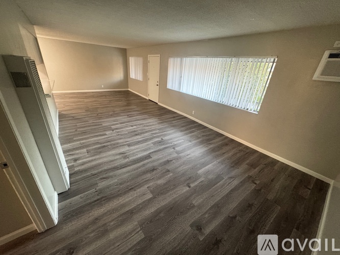 A room with a carpeted floor and a window with blinds.