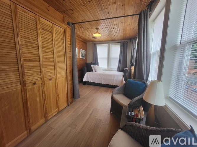 A bedroom with wooden walls and a bed with a white comforter.