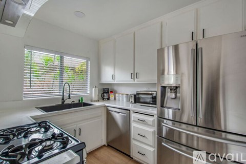 A modern kitchen with a stainless steel refrigerator and a black stove top.