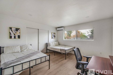 A bedroom with a large bed and a smaller bed with a chair and a desk.