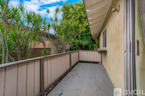 A balcony with a railing and a view of trees and a building.