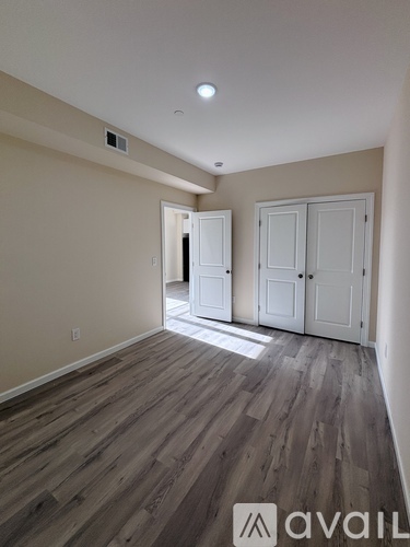 A room with wooden flooring and two white doors.