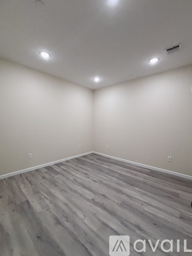 A spacious room with wooden flooring and large windows.