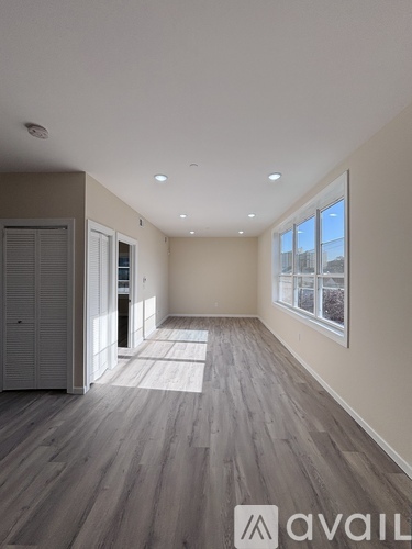 A spacious room with wooden flooring and large windows.