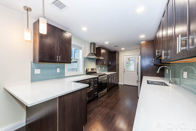 A modern kitchen with dark wood cabinets and white countertops.