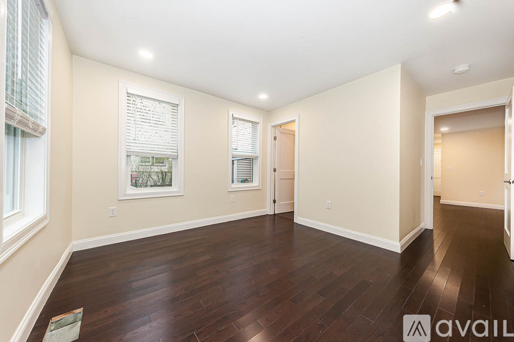 A spacious room with wooden floors and white walls.