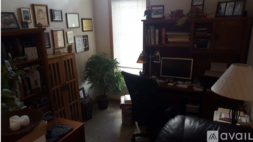 A room with a desk, chair, and bookshelf filled with books and picture frames.
