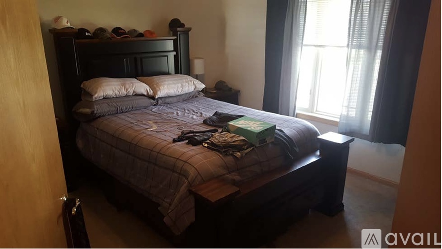 A bed with a grey comforter and two pillows is in a room with a window.