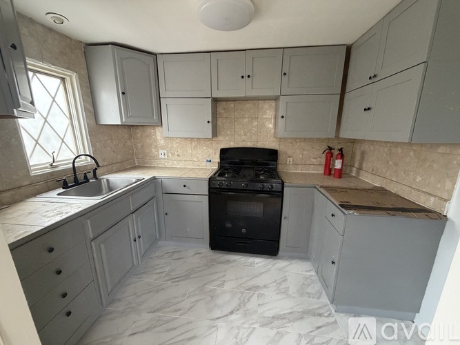 A kitchen with a black stove top oven and a marble counter top.