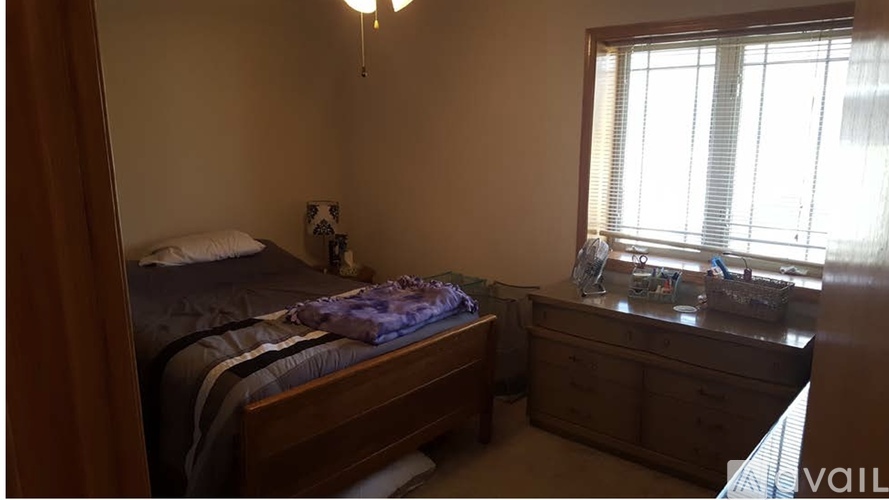 A bedroom with a bed, nightstand, and window.