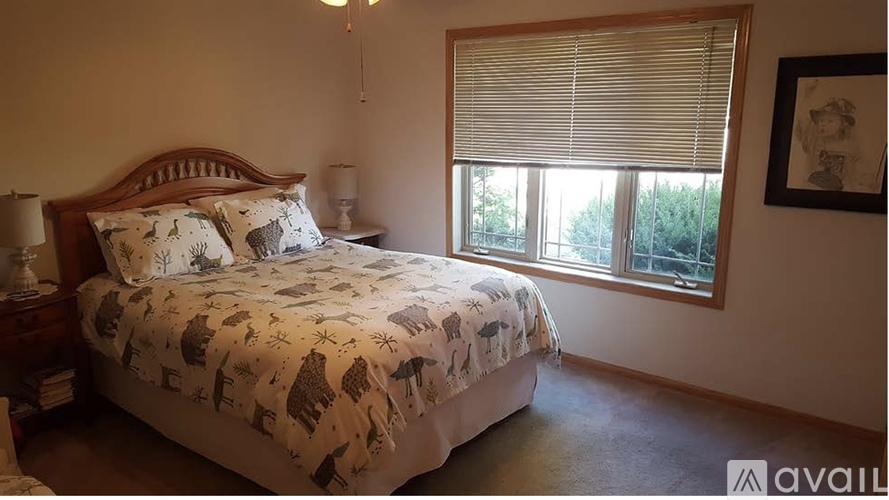 A bedroom with a bed, nightstand, lamp, and window with blinds.