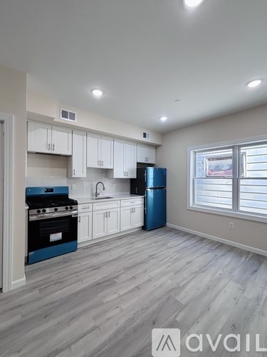 A kitchen with white cabinets and a blue refrigerator.