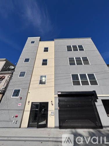 A tall building with a closed black door and windows on the side.
