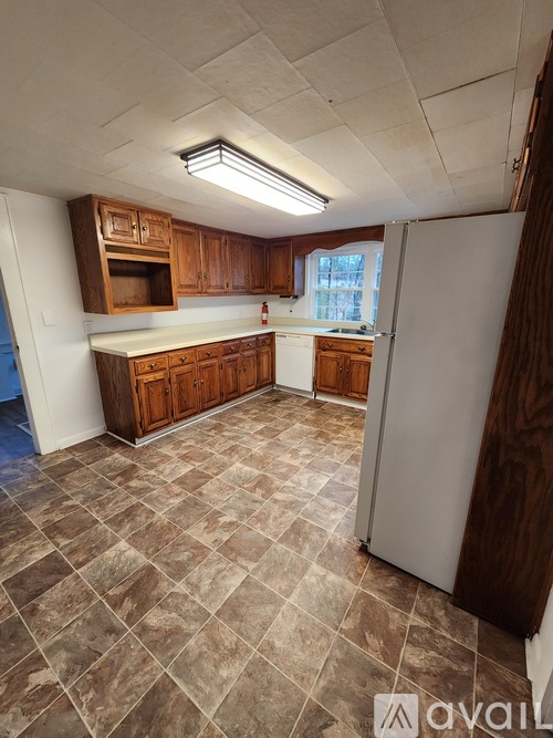 A kitchen with brown cabinets and a tiled floor.