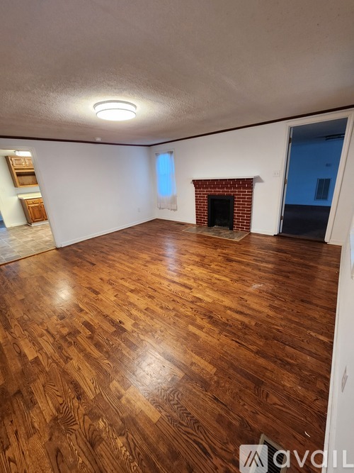 A room with wooden flooring and a fireplace.