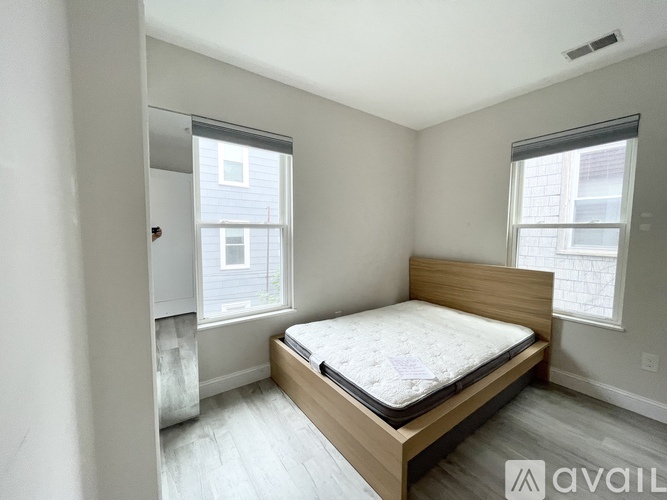 A bedroom with a bed, wooden headboard, and two windows.