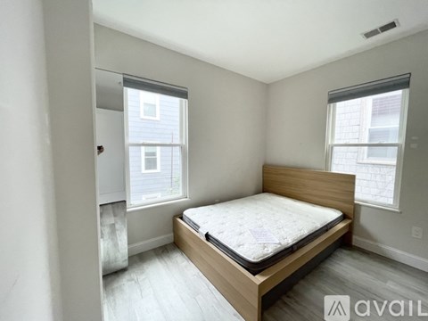 A bedroom with a bed, wooden headboard, and two windows.