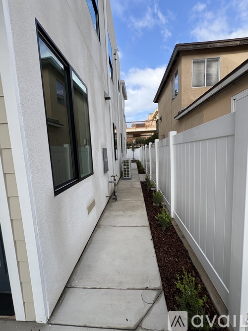 A white fence runs along the side of a building.