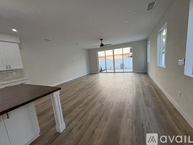 A spacious room with wooden flooring and white walls.