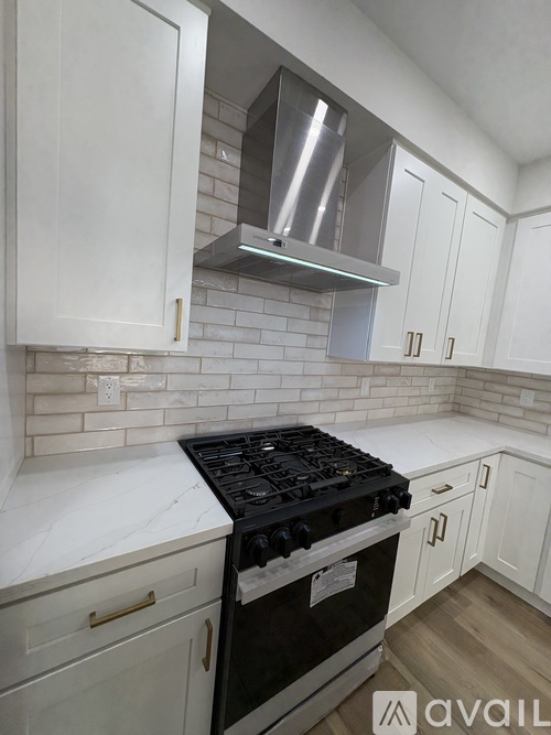 A kitchen with white cabinets and a black stove top.