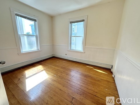 A room with wooden floors and two windows.