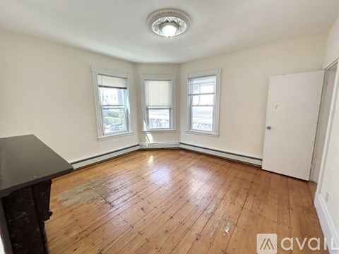 A room with wooden floors and three windows.