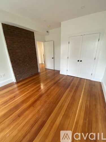 A room with wooden flooring and a brick wall.