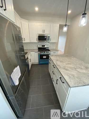 A kitchen with a stainless steel refrigerator and a granite countertop.