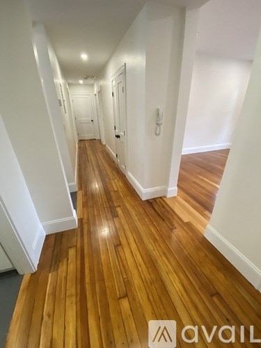 A hallway with wooden floors and white walls.
