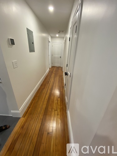 A long hallway with wood floors and white walls.