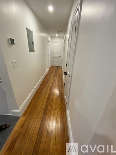 A long hallway with wood floors and white walls.