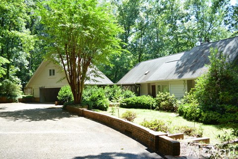 A covered deck with a table and chairs overlooking a wooded area.