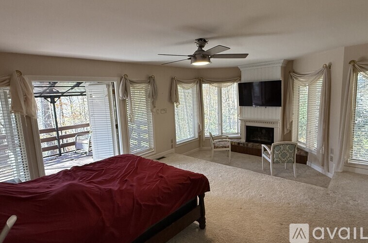 A bedroom with a red bedspread and a television mounted on the wall.