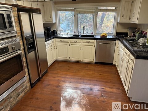 A kitchen with white cabinets and a wooden floor.