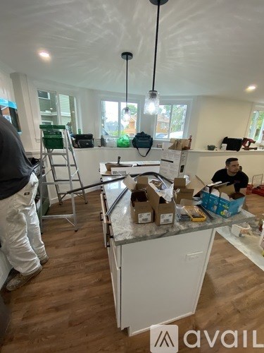 A man is working on a kitchen renovation with boxes of cabinets and appliances.