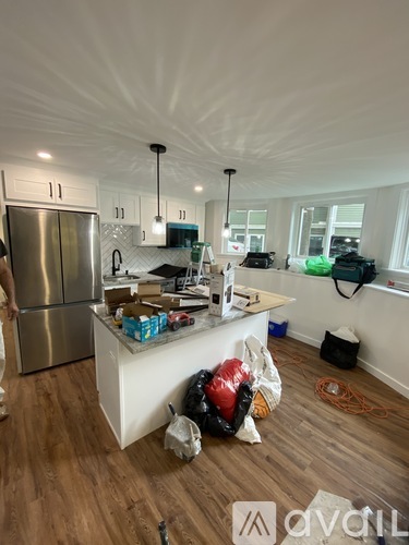 A kitchen with a refrigerator, a counter, and a person standing in the room.