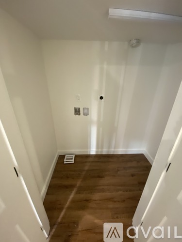 A hallway with a wooden floor and white walls.