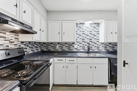A kitchen with white cabinets and a black stove top.