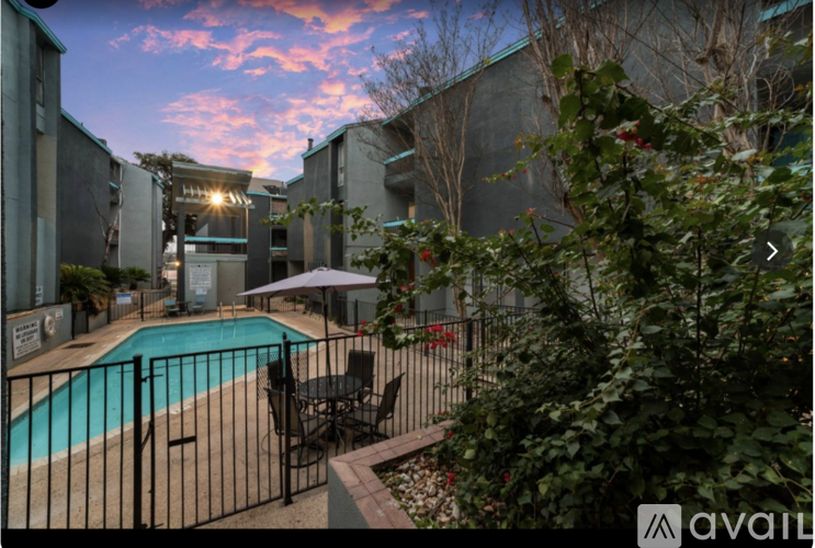 A pool area with a table and chairs and a building in the background.